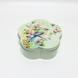 Our products: Korbdose mit Frühlingsmotiv und Singvogel als Geschenkverpackung für Ostern. Stülpdeckeldose in Blütenform aus Weißblech. Draufsicht auf Deckel